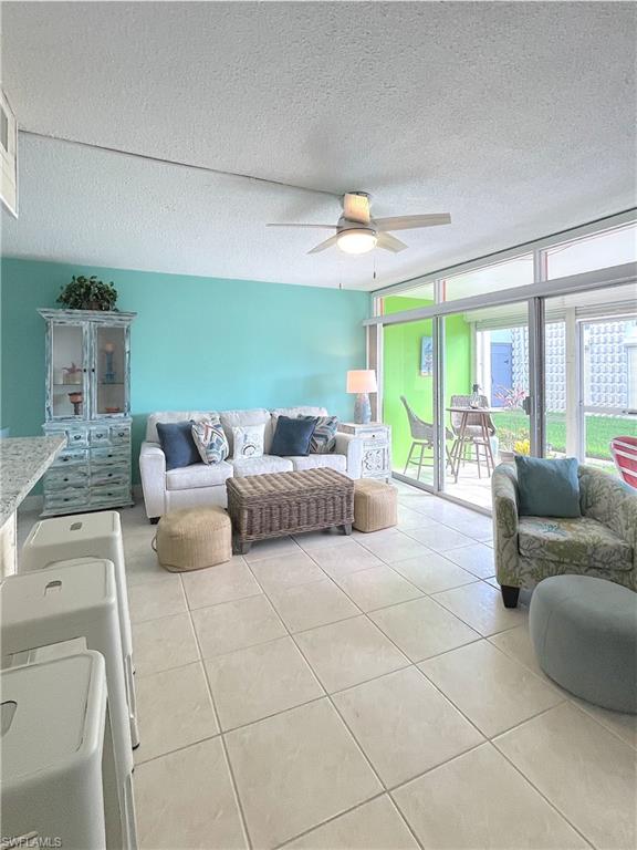 Living area with a ceiling fan, a textured ceiling, and tile patterned flooring