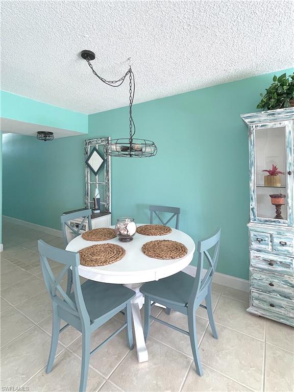 Tiled dining area featuring a textured ceiling and a chandelier