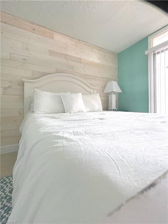 Bedroom featuring wood walls and a textured ceiling