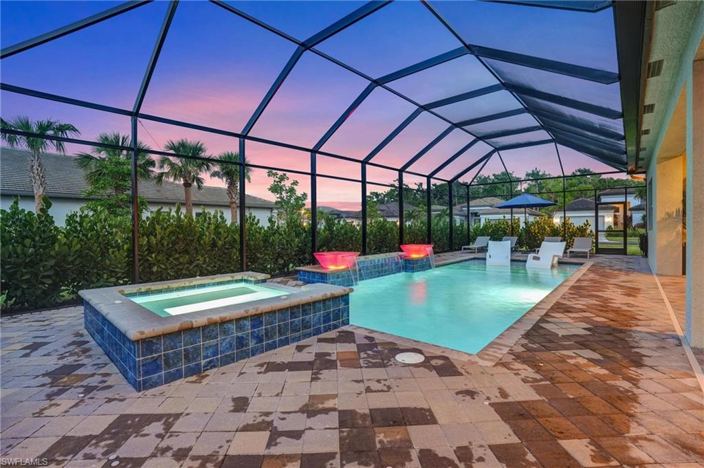 Pool at dusk with a patio area, a lanai, and a pool with connected hot tub