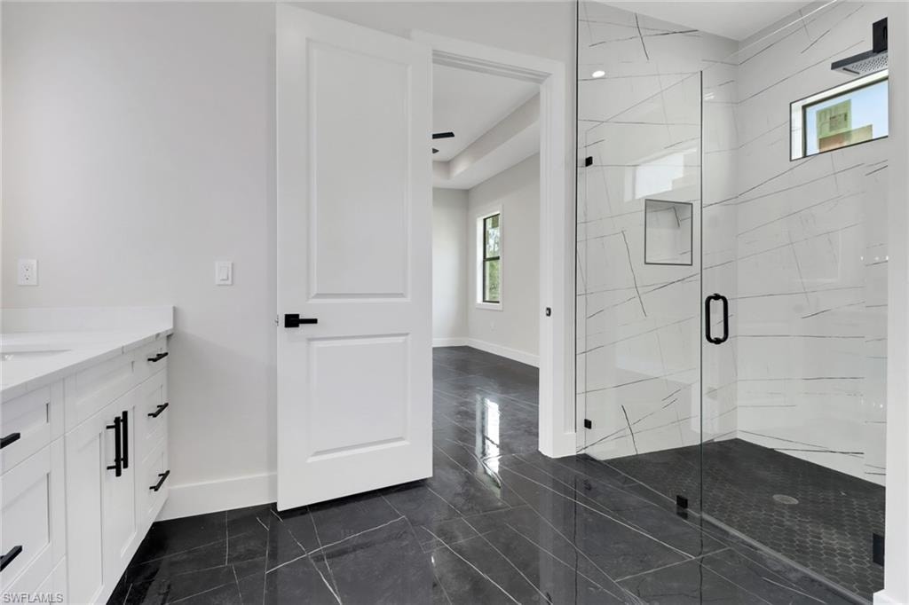 Primary Bathroom featuring vanity, tile flooring and upgraded shower with frameless glass door