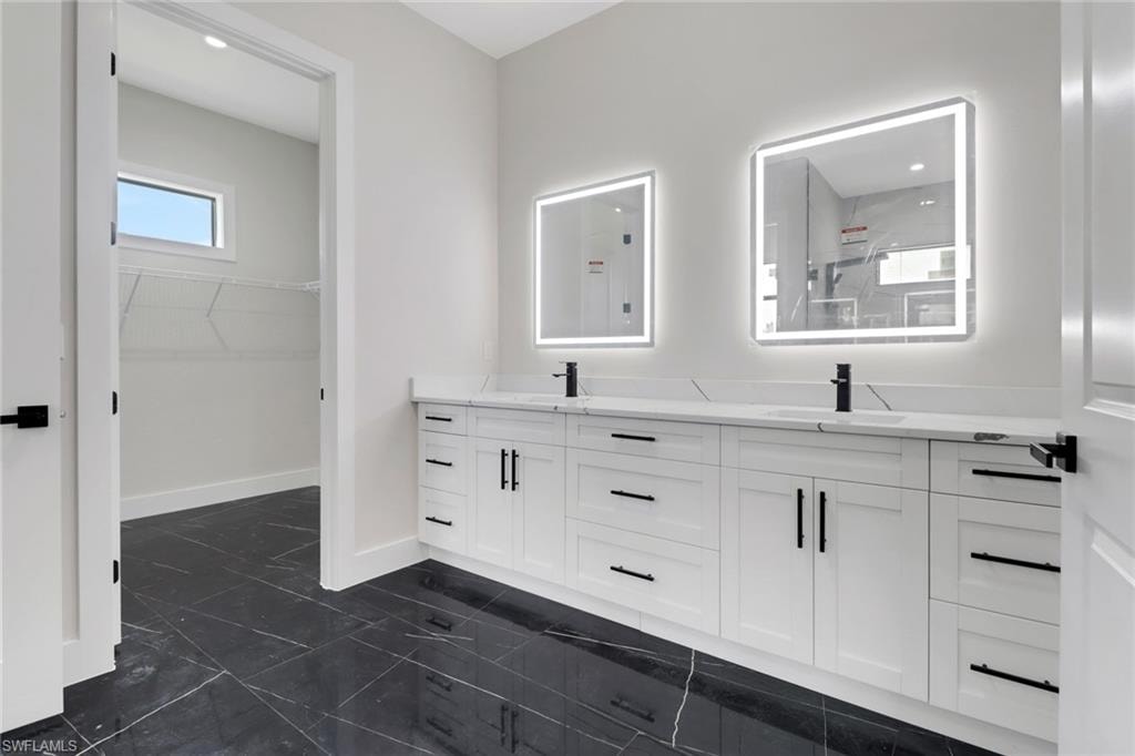 Primary bathroom with dual vanity, tile floors and entrance to walk in closet