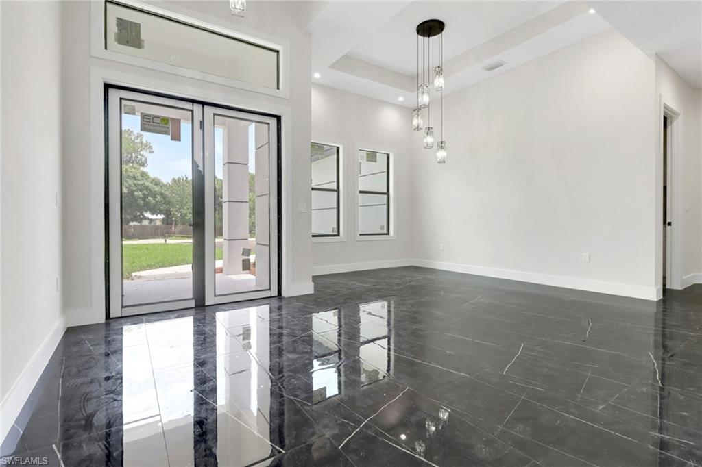 Foyer with glass entry doors and dining area with upgraded modern lighting