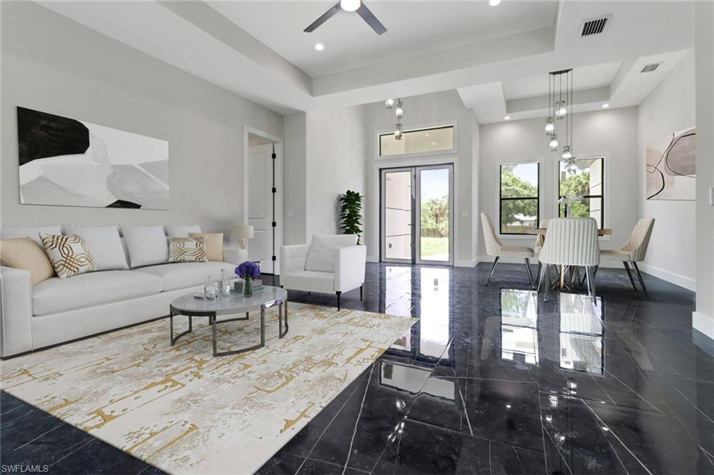 Living room featuring a tray ceiling, ceiling fan, and french doors