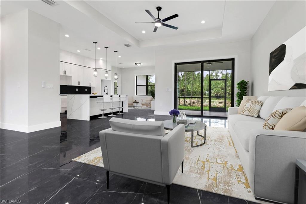 Living room featuring a raised ceiling, recessed lighting, and ceiling fan