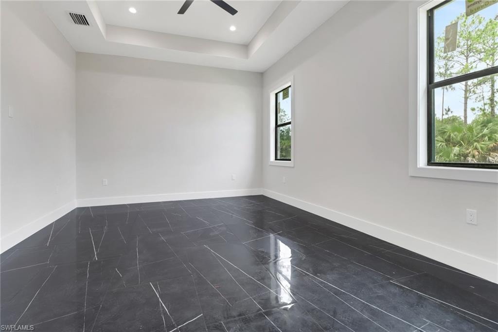Primary bedroom featuring tile flooring, tray ceiling, recessed lighting and a ceiling fan
