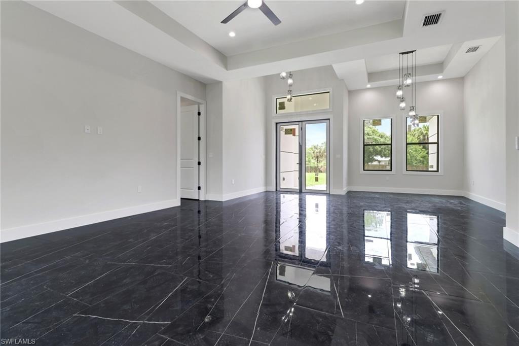 Great room featuring a tray ceiling with ceiling fan, modern light fixtures and tile flooring