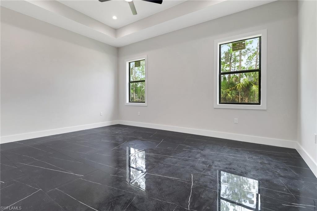 Primary bedroom with tile floors, tray ceiling, recessed lighting and ceiling fan