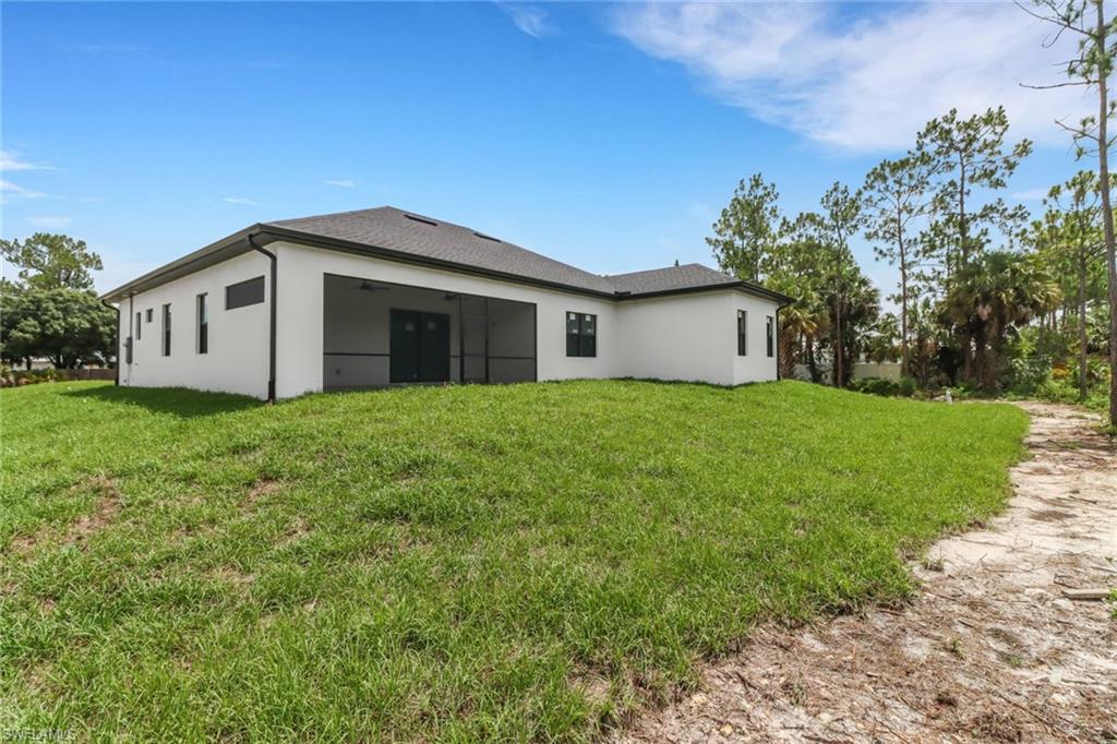 Back of property featuring a screened lanai and landscaped area