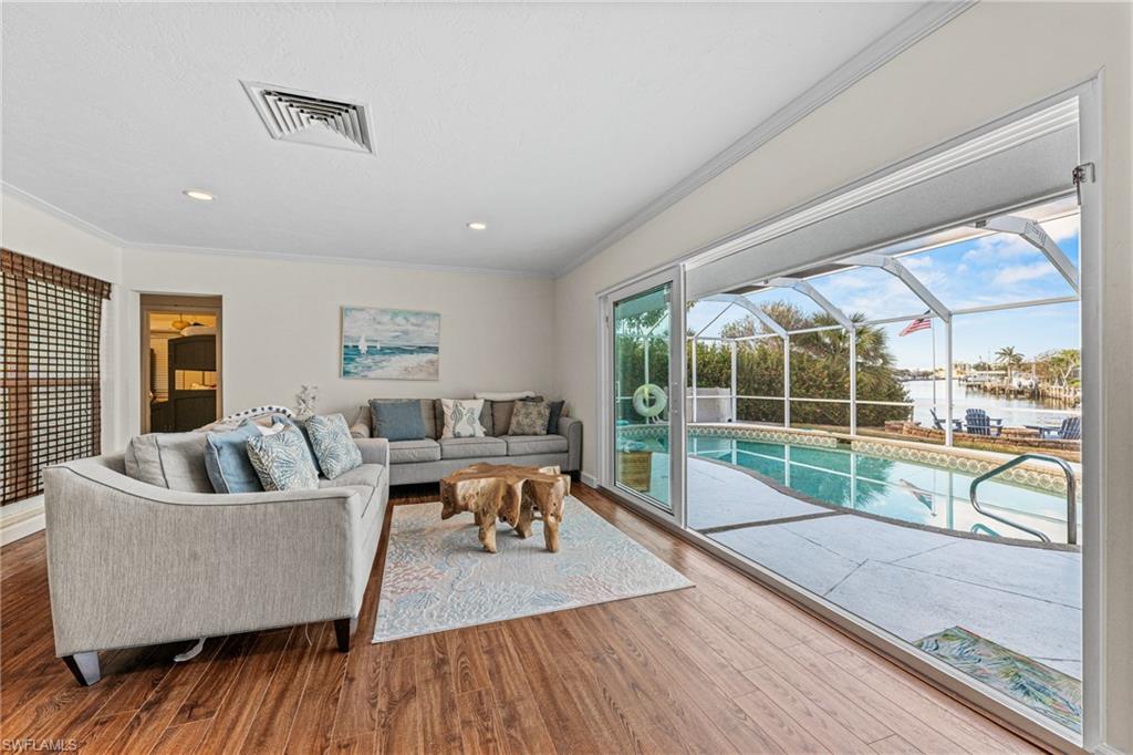 Living area with ornamental molding, wood finished floors, recessed lighting, and a water view