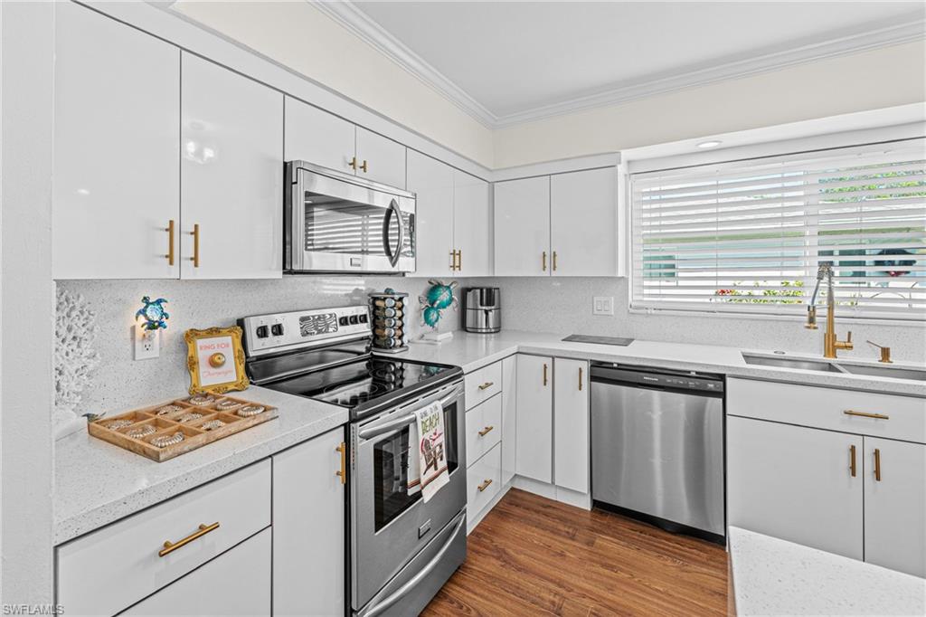 Kitchen featuring stainless steel appliances, crown molding, white cabinets, decorative backsplash, and dark wood-style floors