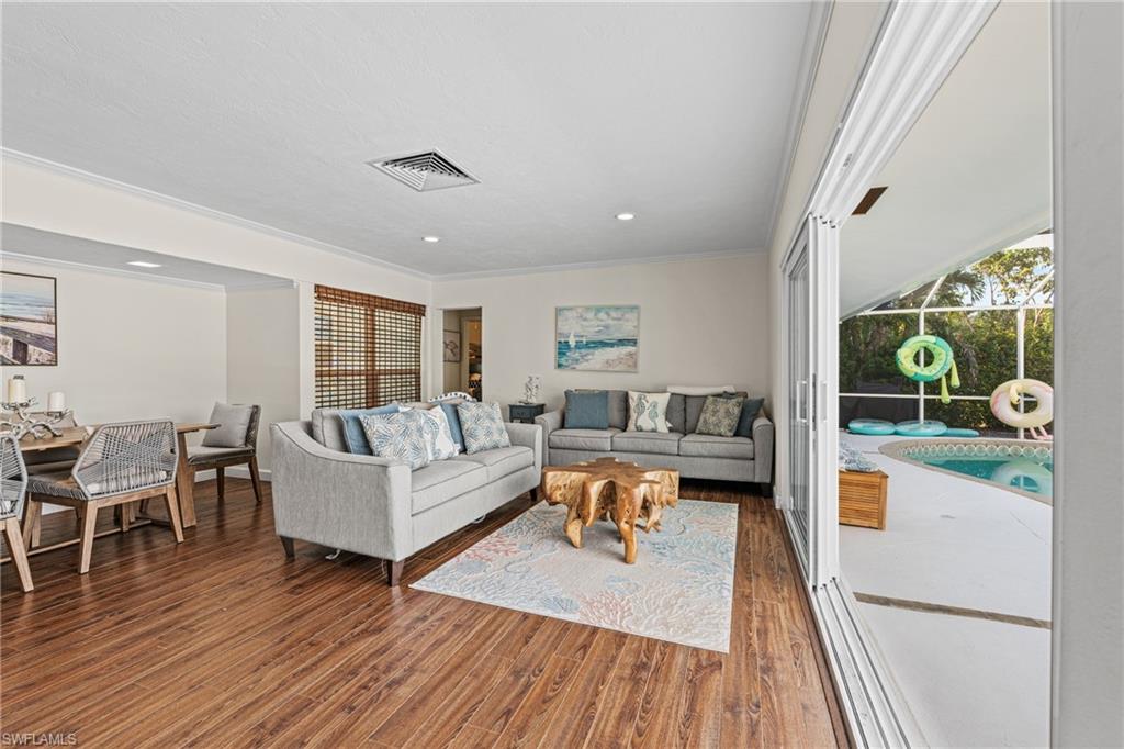 Living area with wood finished floors, crown molding, and recessed lighting