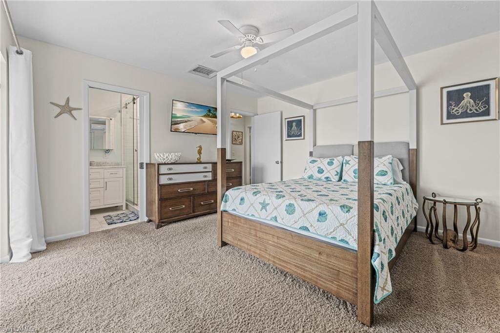 Bedroom featuring light colored carpet, a ceiling fan, and connected bathroom