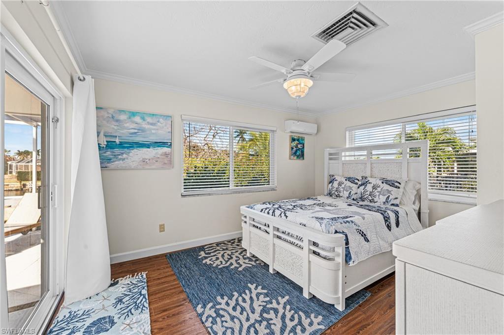 Bedroom featuring ornamental molding, an AC wall unit, access to outside, dark wood finished floors, and a ceiling fan