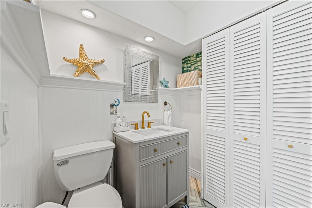 Bathroom with a closet, vanity, and recessed lighting