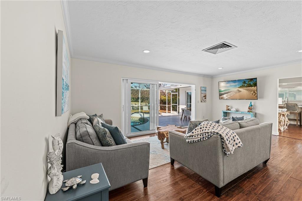 Living area featuring ornamental molding, dark wood-type flooring, a textured ceiling, and recessed lighting