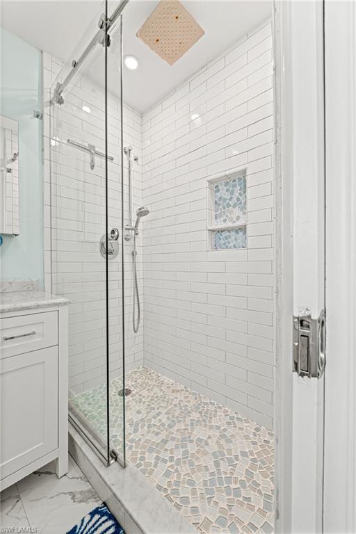 Bathroom with a stall shower, recessed lighting, marble look tiles, and vanity