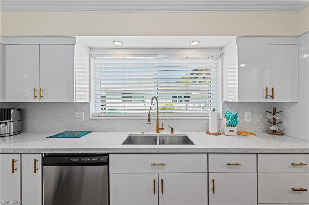 Kitchen featuring stainless steel dishwasher, ornamental molding, white cabinetry, light countertops, and backsplash