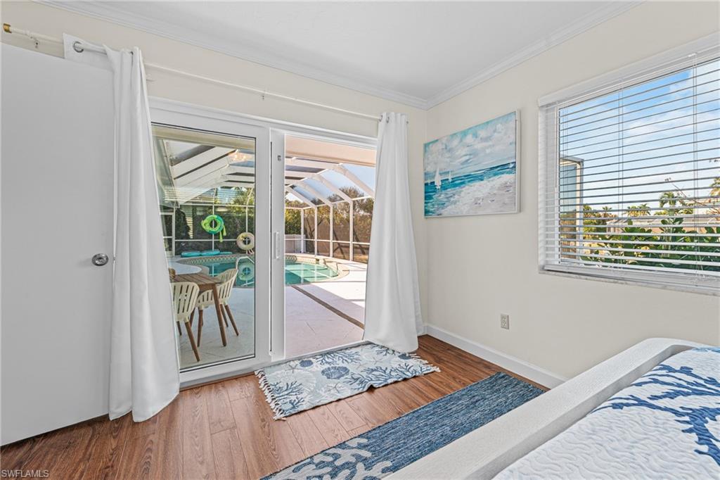 Bedroom featuring crown molding, access to outside, and wood finished floors