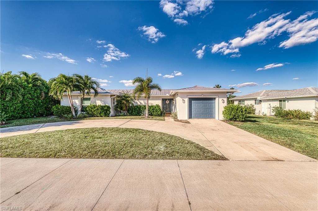 Single story home with driveway, stucco siding, a front yard, and a garage