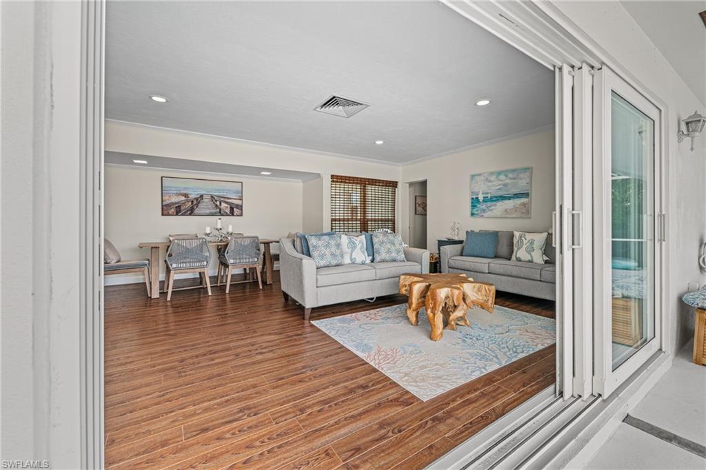 Living area featuring wood finished floors, ornamental molding, and recessed lighting
