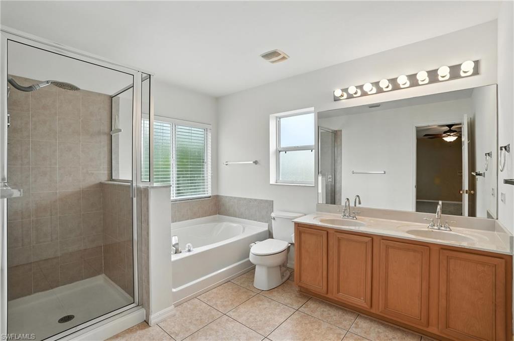 Full bath with a garden tub, a shower stall, double vanity, tile patterned floors, and ceiling fan