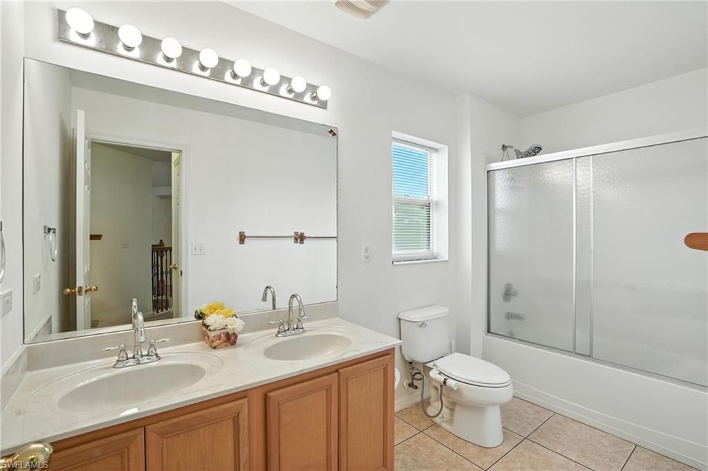 Bathroom with double vanity, tile patterned flooring, and bath / shower combo with glass door