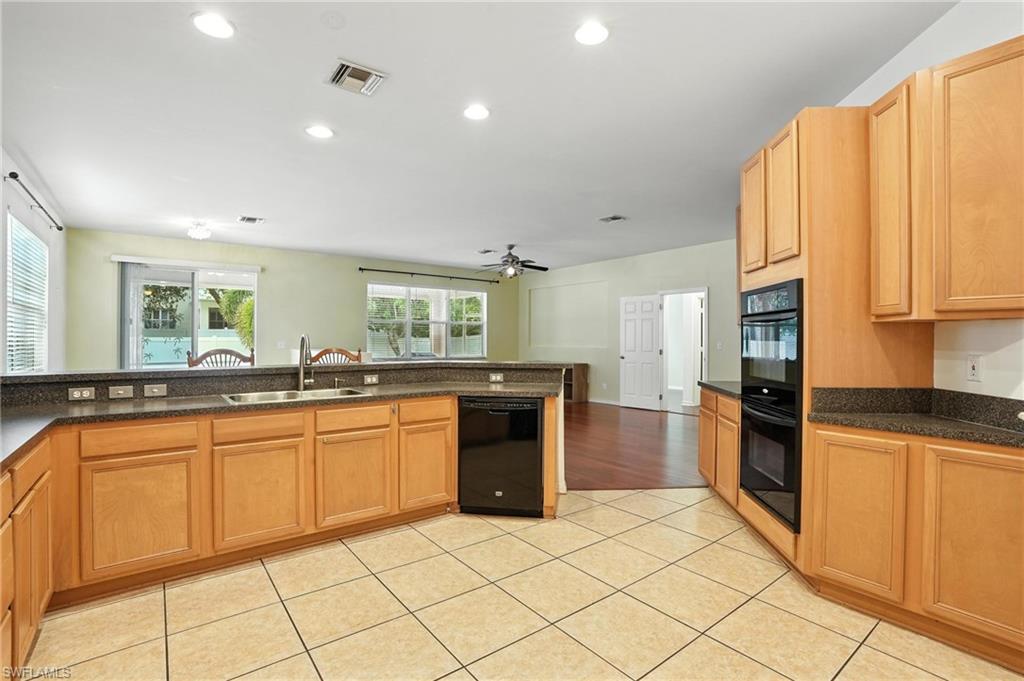 Kitchen featuring black appliances, a ceiling fan, dark countertops, light tile patterned flooring, and recessed lighting