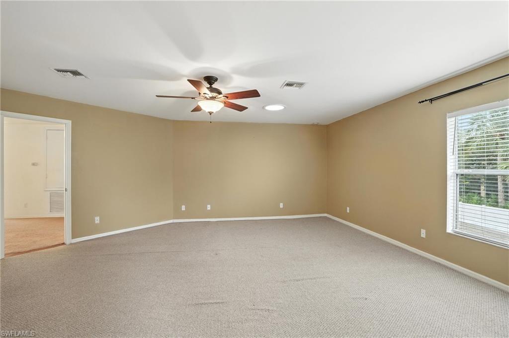 Empty master bedroom with a ceiling fan and carpet flooring