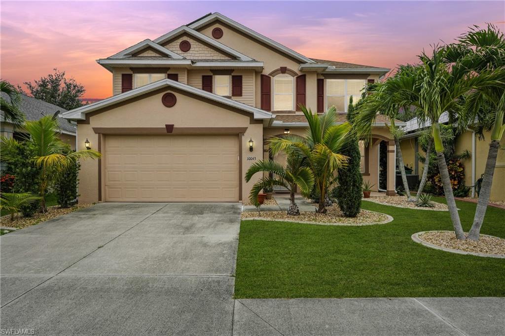 View of front of house with stucco siding, concrete driveway, a front yard, and an attached garage