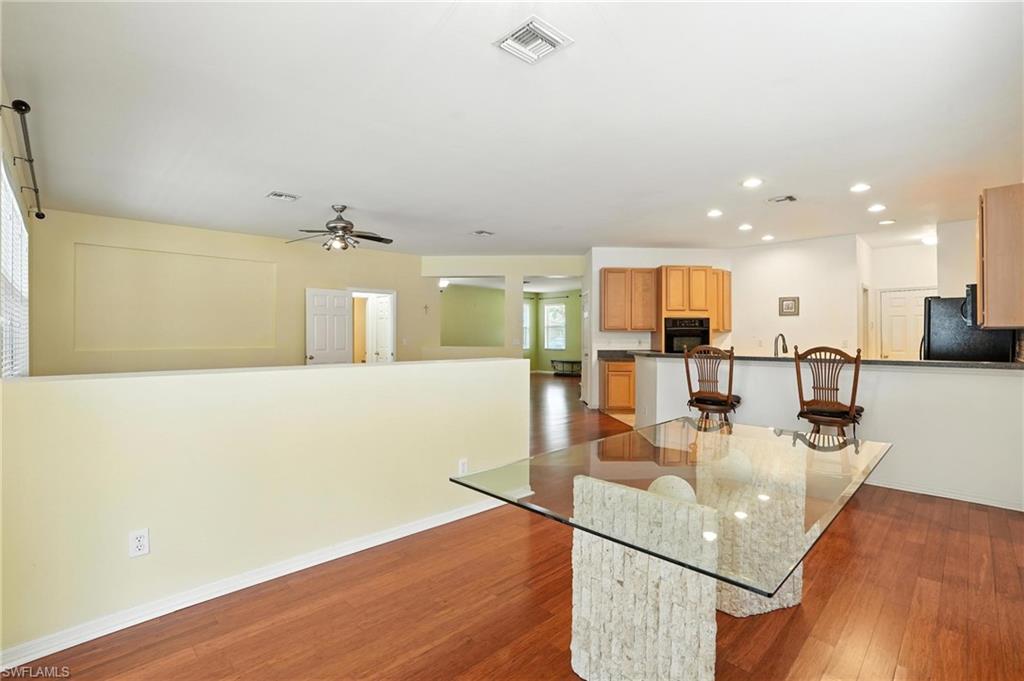 Kitchen with black appliances, recessed lighting, wood finished floors, ceiling fan, and a kitchen bar