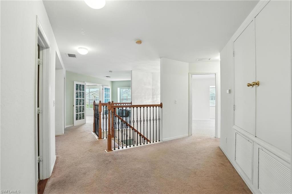 Hall featuring an upstairs landing and light carpet