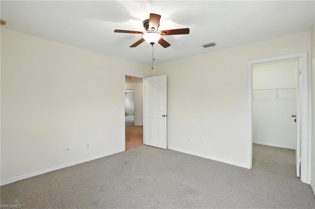 Unfurnished bedroom featuring carpet flooring, a spacious closet, a closet, and ceiling fan