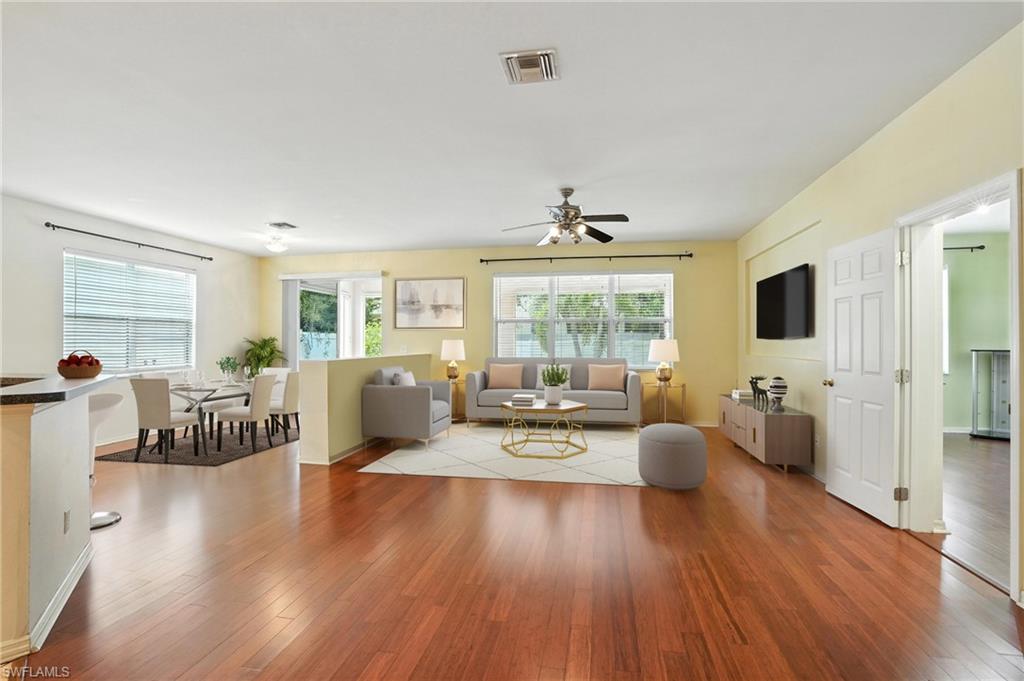 Living area with wood finished floors and a ceiling fan (Virtually Staged)