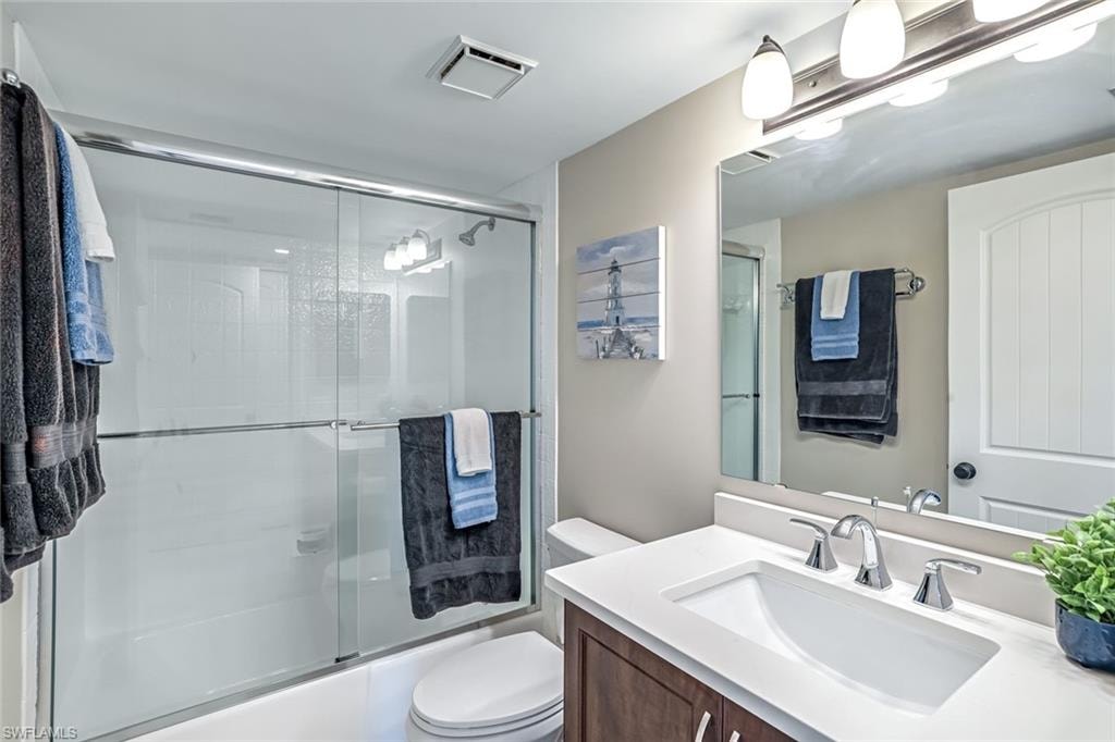 Bathroom featuring vanity and bath / shower combo with glass door