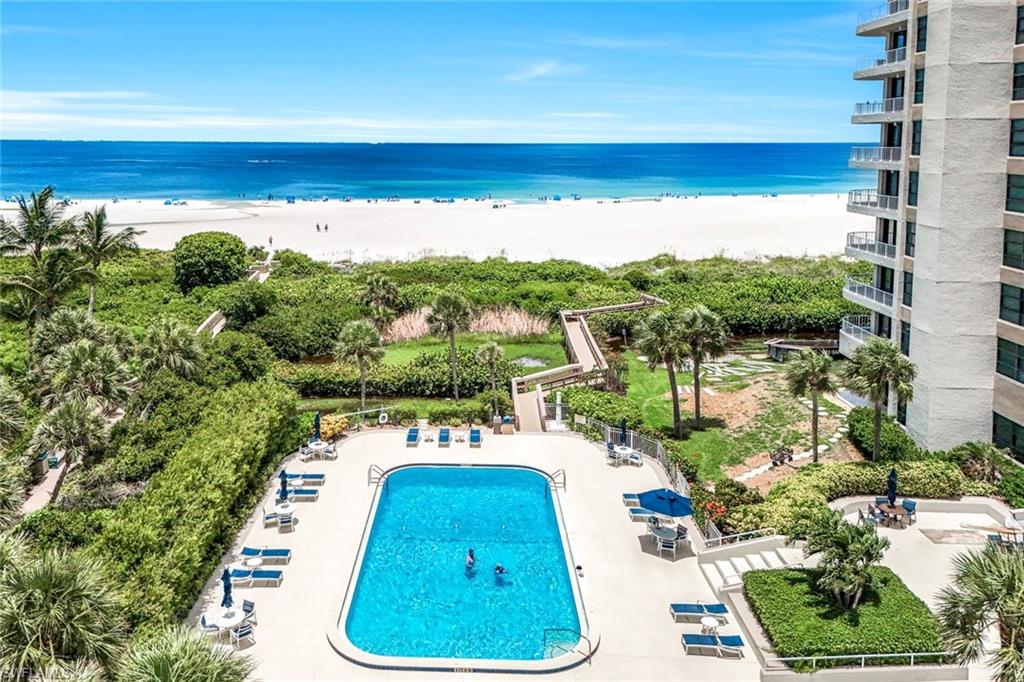 Community pool featuring a patio and view of water and beach