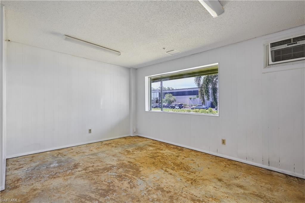 Spare room with an AC wall unit, a textured ceiling, and concrete flooring