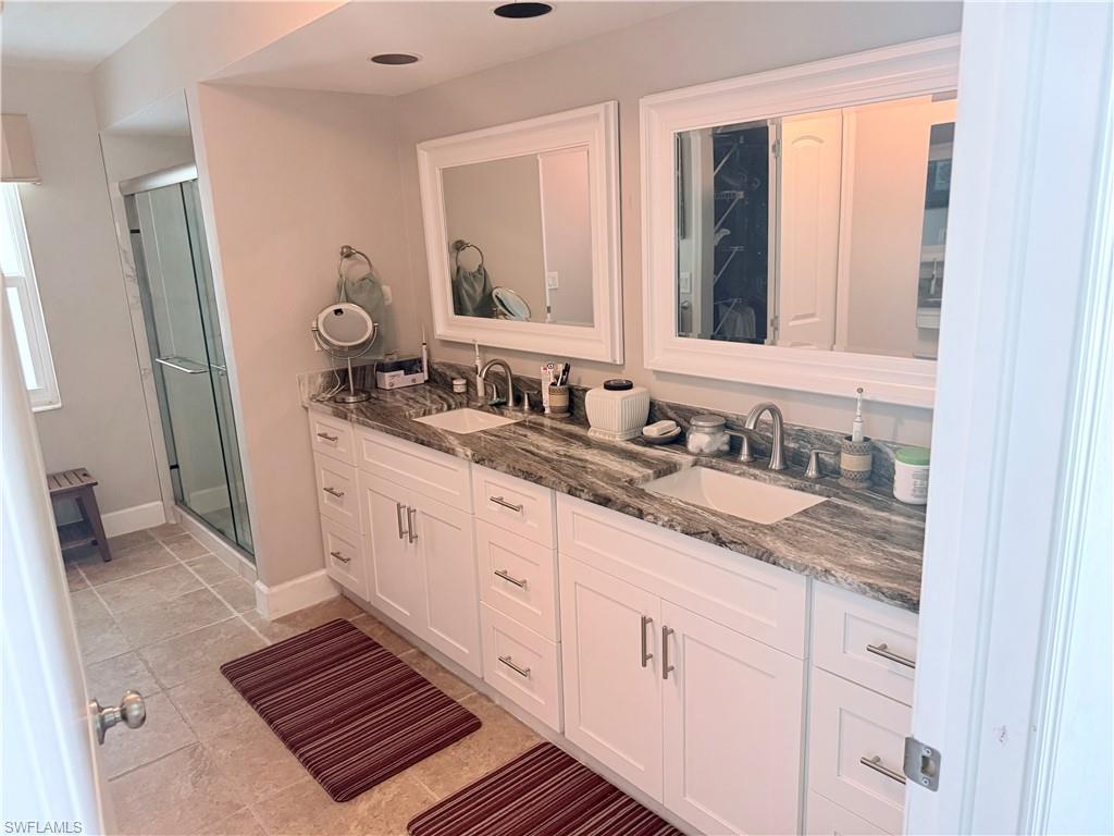 Bathroom with double vanity, a stall shower, and tile patterned floors
