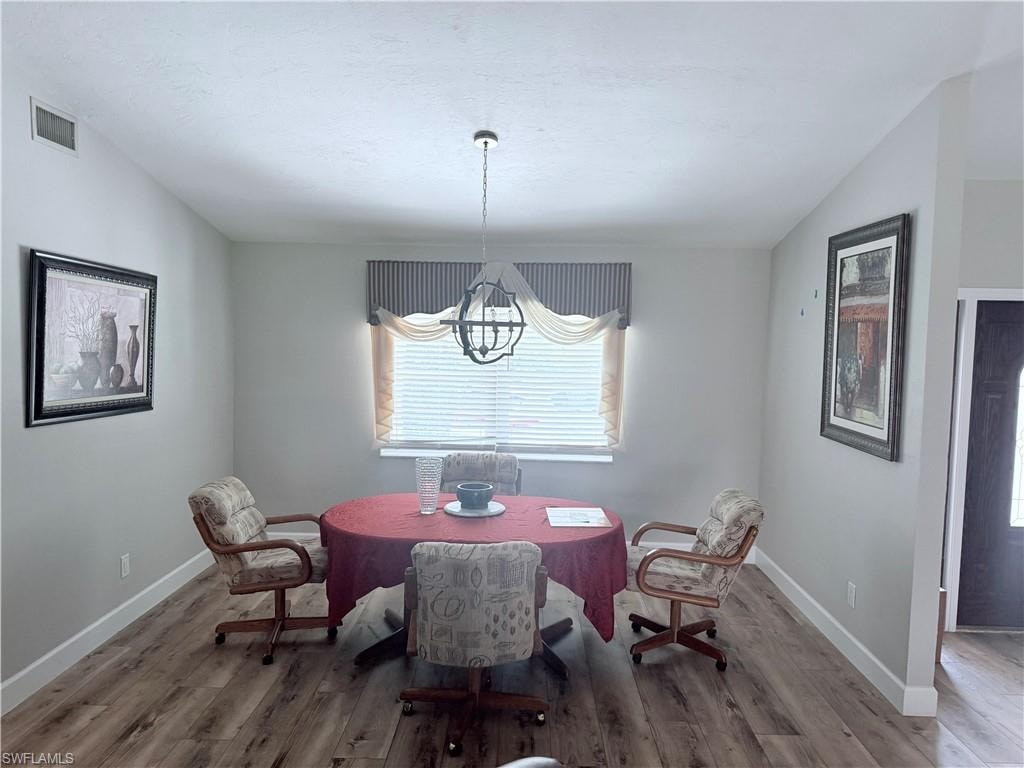 Dining area with a chandelier, wood finished floors, and vaulted ceiling