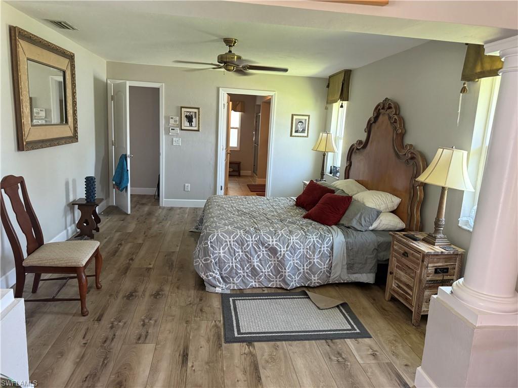 Bedroom featuring ornate columns, wood finished floors, and a ceiling fan