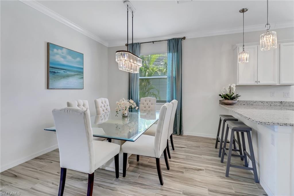 Dining space featuring a chandelier, ornamental molding, and light wood-style flooring