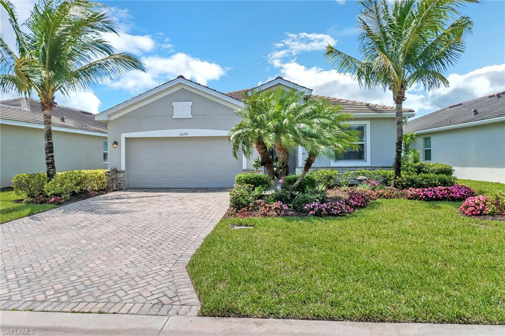 View of front of house with stucco siding, decorative driveway, a garage, a front lawn, and a tile roof