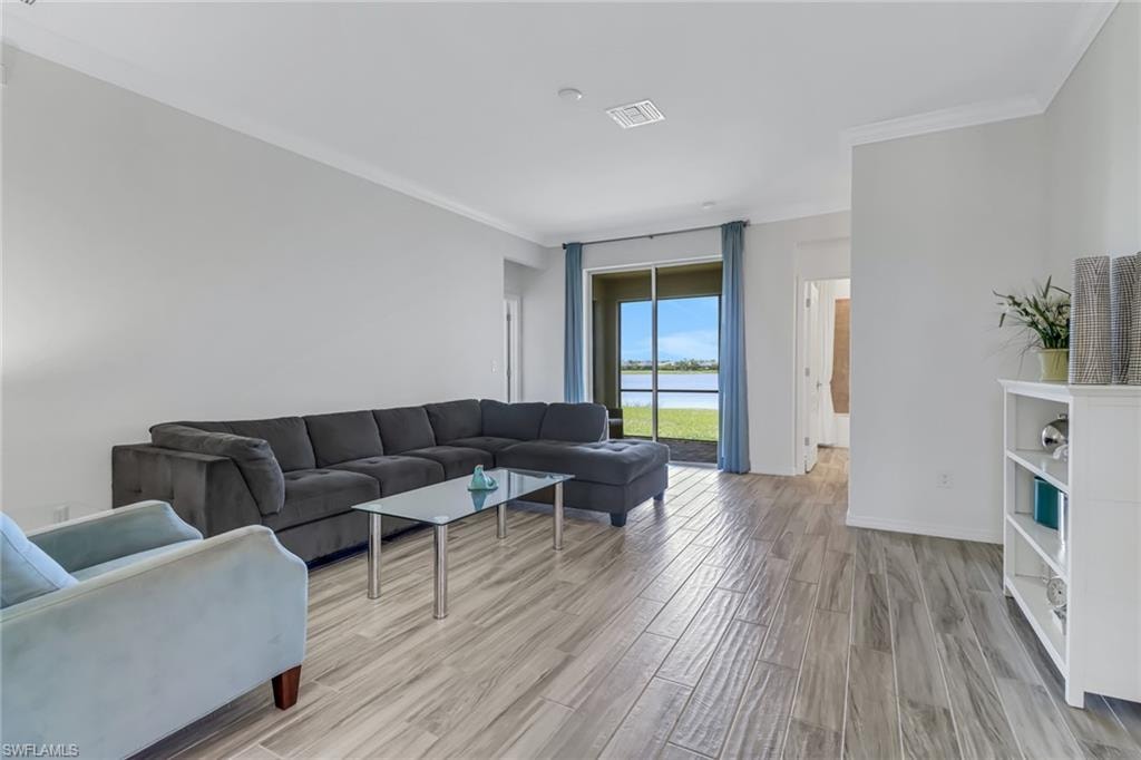 Living room with ornamental molding, light wood finished floors, and a water view