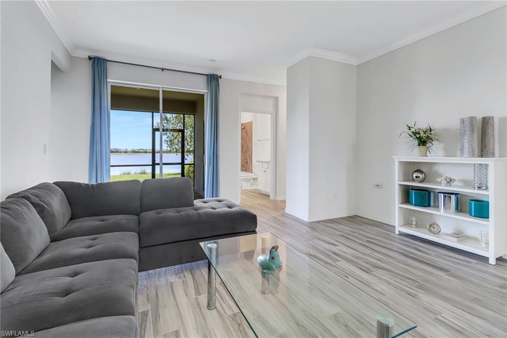 Living room with crown molding, light wood-type flooring, and a water view