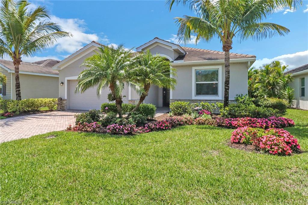 View of front facade featuring decorative driveway, a tiled roof, an attached garage, stucco siding, and a front lawn