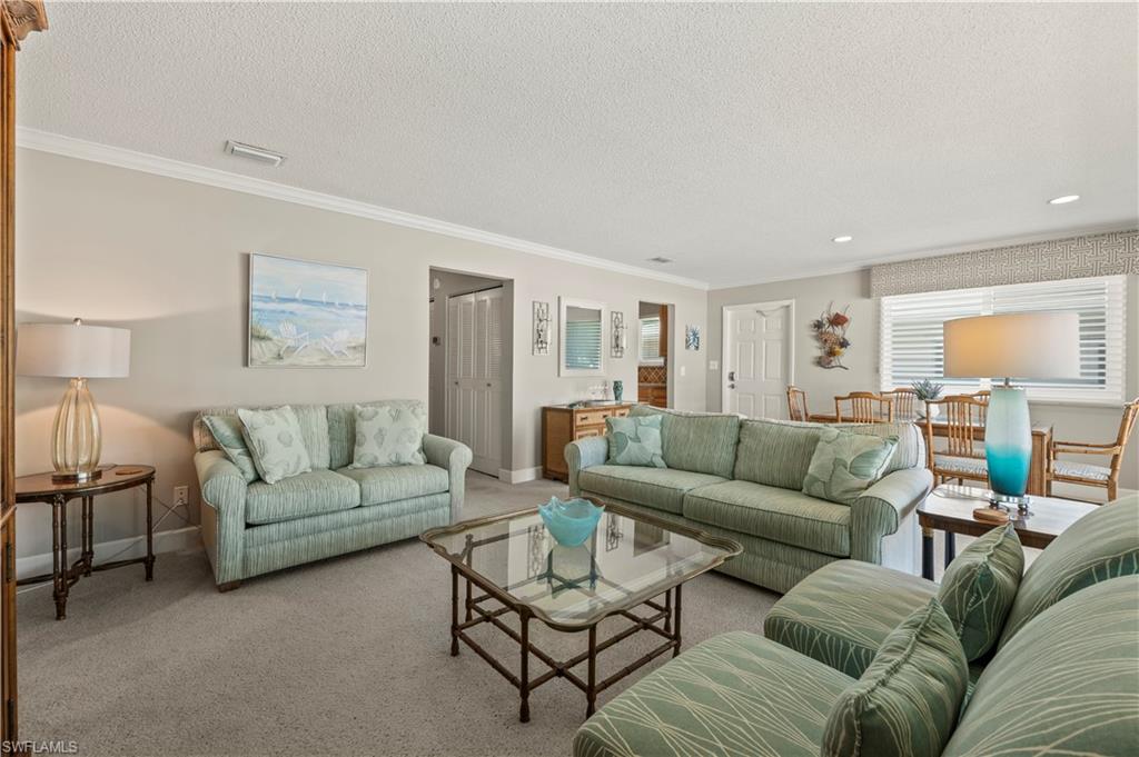 Carpeted living area with crown molding, a textured ceiling, and recessed lighting