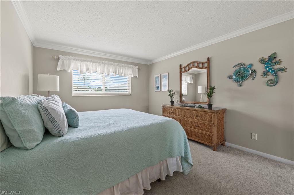 Bedroom featuring ornamental molding, a textured ceiling, and carpet