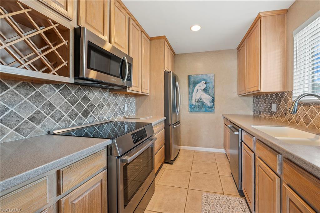 Kitchen featuring stainless steel appliances, light tile patterned flooring, decorative backsplash, light countertops, and recessed lighting