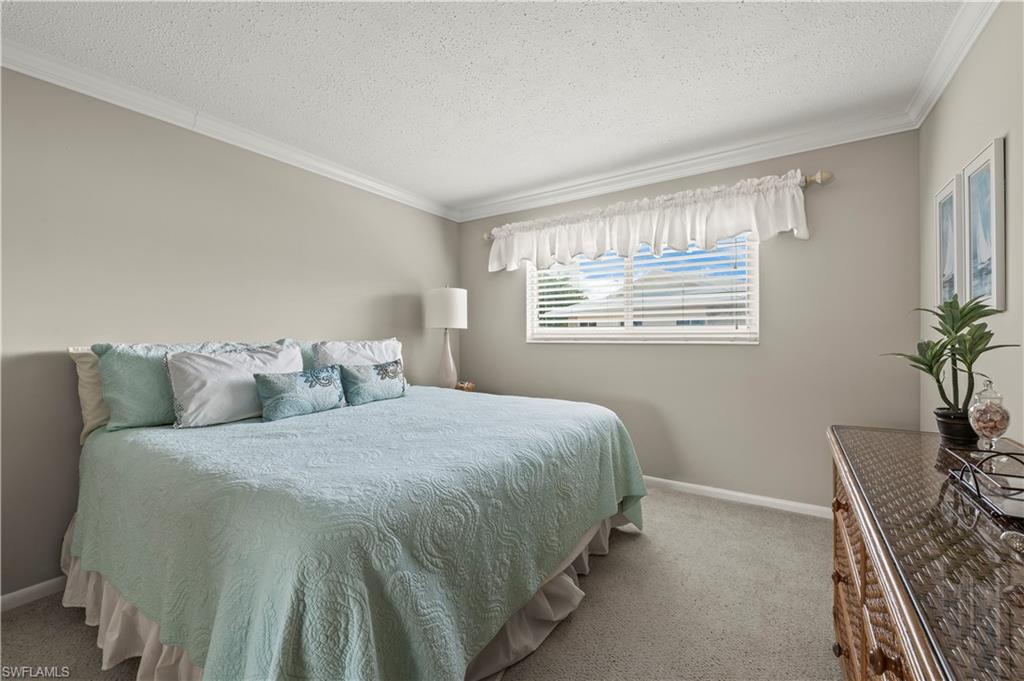 Bedroom with ornamental molding, a textured ceiling, and carpet floors