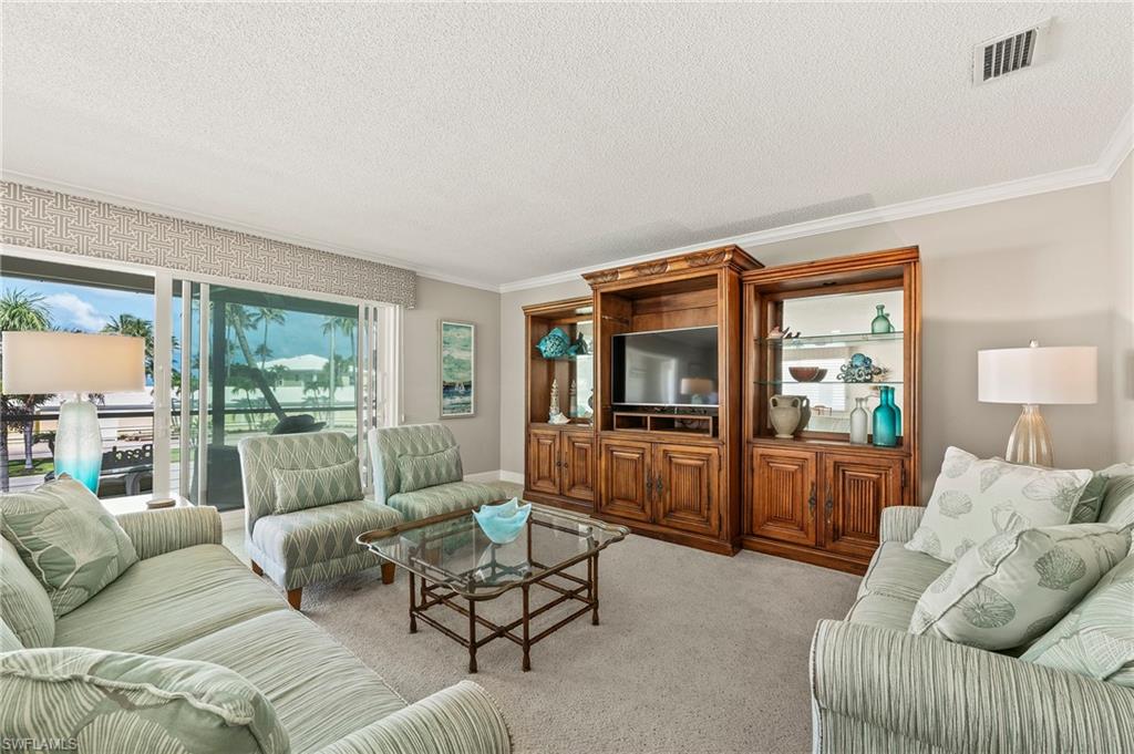 Living room with ornamental molding, a textured ceiling, and light carpet